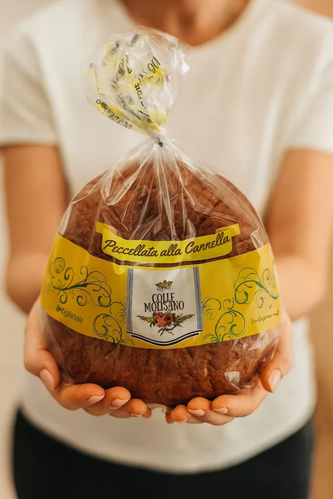 Persona che tiene in mano una Peccellata alla Cannella Colle Molisano, dolce artigianale molisano confezionato con etichetta gialla